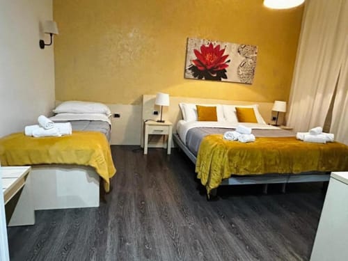 Camera luminosa giallo sole in AD Trastevere con due letti, biancheria bianca e servizi moderni a Roma