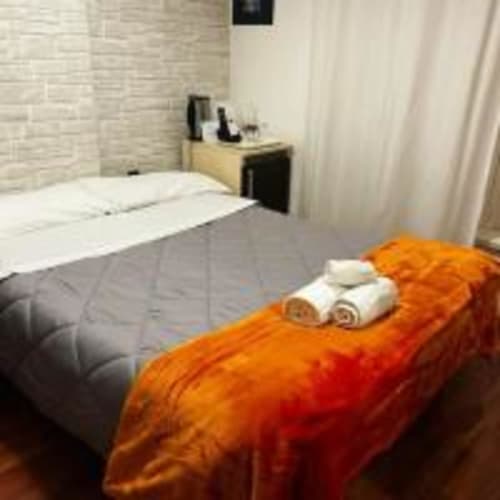 Camera moderna dell'AD Trastevere Guest House Roma con coperta arancione e asciugamani arrotolati sul letto