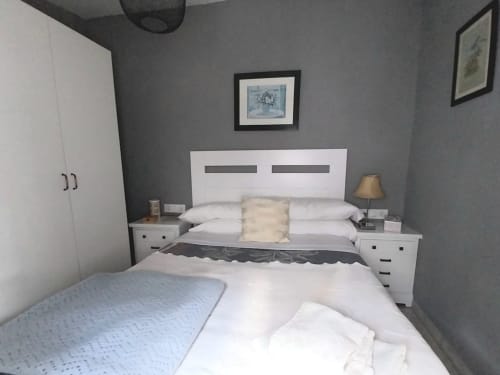 Dormitorio moderno en apartamento Top Home Integra en Jerez de la Frontera con cama blanca, mesillas y paredes grises
