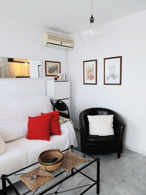 Apartamento estudio moderno en Jerez de la Frontera con sofá blanco, sillón negro y cuadros en las paredes