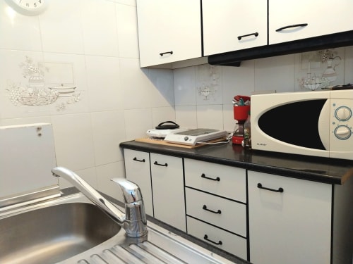 Cocina moderna con muebles blancos, microondas y fregadero de acero inoxidable en el apartamento Top Home Integra, Jerez de la Frontera