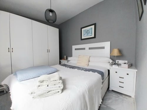 Moderno dormitorio en el apartamento Top Home Integra de Jerez de la Frontera con cama blanca, armario, mesita de noche y paredes grises