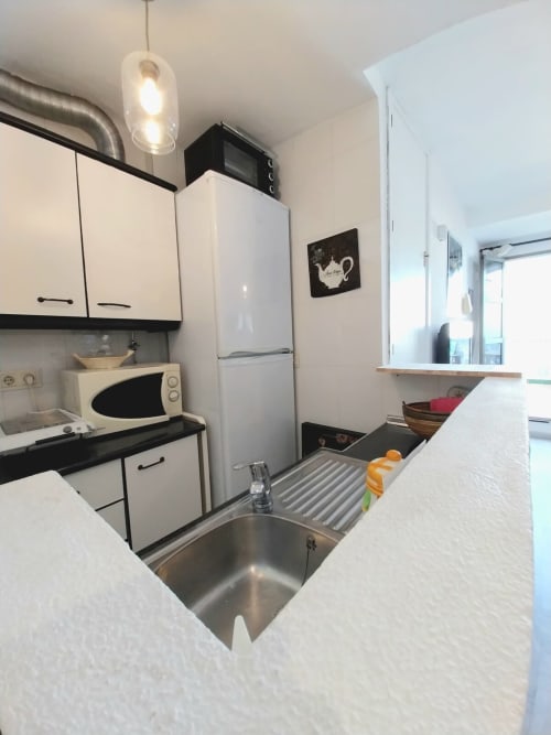 Moderna cocina compacta en apartamento Top Home Integra, Jerez de la Frontera, con muebles blancos, fregadero de acero inoxidable y