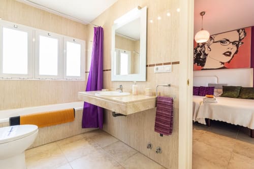 Baño moderno con azulejos beige, detalles en púrpura y lavamanos en apartamento Top Home Integra de Jerez de la Frontera