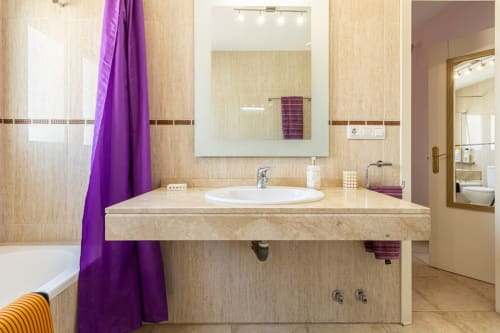 Cuarto de baño moderno en apartamento Top Home Integra en Jerez de la Frontera con lavabo de mármol, detalles en púrpura y vistas a la ciudad