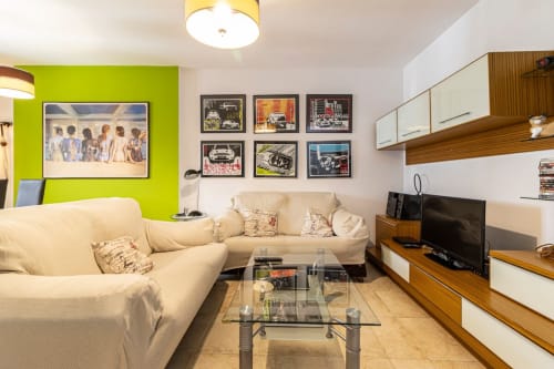 Moderno salón en Top Home Integra, Jerez de la Frontera, con pared verde lima, sofá crema y vistas a la ciudad