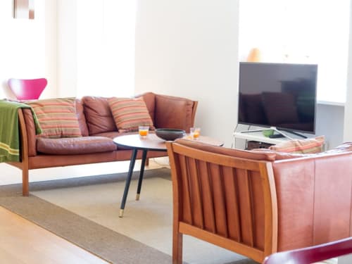 Moderno salón en apartamento Top Home Integra de Jerez de la Frontera con sofás de cuero, TV y vistas a la ciudad