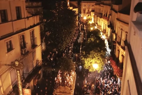 Bulliciosa calle nocturna en Jerez de la Frontera con edificios históricos iluminados cálidamente y multitudes