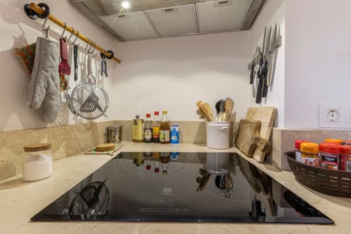 Moderno mostrador de cocina con placa de inducción, organizadores de utensilios y esenciales culinarios en Top Home Integra