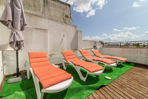 Tumbonas naranjas sobre césped artificial en la terraza de la azotea del apartamento Top Home Integra en Jerez