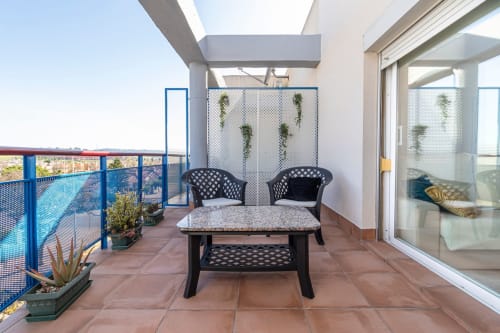 Terraza moderna con mobiliario negro, vistas a la montaña y plantas trepadoras en el apartamento Top Home Integra de Jerez de la Frontera