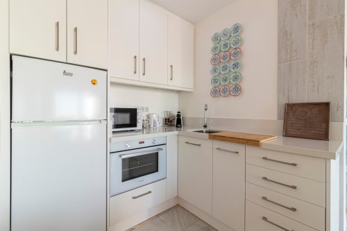 Cocina moderna con muebles blancos, electrodomésticos de acero inoxidable y platos decorativos en el apartamento Top Home Integra de Jerez