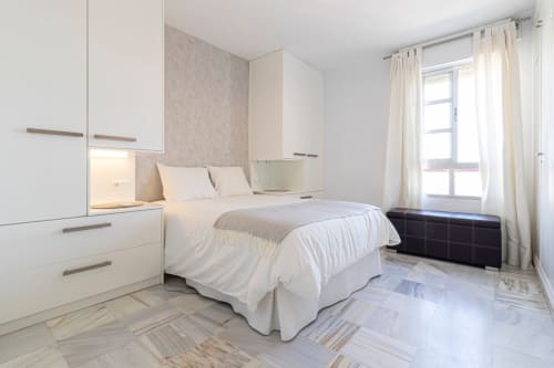 Dormitorio moderno en apartamento Top Home Integra de Jerez de la Frontera con armarios empotrados blancos, cama y vistas a la sierra