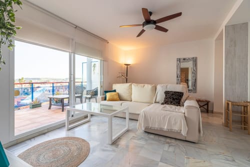 Apartamento moderno en Top Home Integra, Jerez de la Frontera, con sofá crema, ventilador de techo y vistas a la montaña desde el balcón