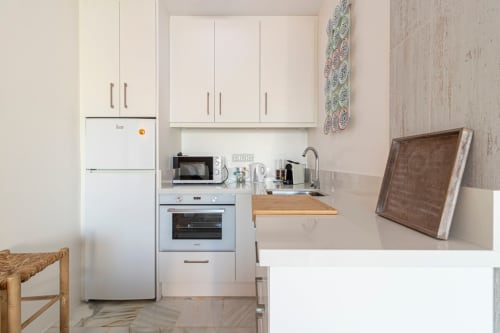 Moderna cocina del apartamento Top Home Integra en Jerez de la Frontera con muebles blancos, electrodomésticos y detalles de madera