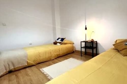 Dormitorio doble en apartamento Top Home Integra, Jerez de la Frontera, con ropa de cama amarilla y mobiliario moderno