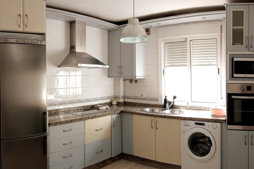 Cocina moderna en apartamento Top Home Integra, Jerez de la Frontera con muebles blancos, encimeras de granito y acero inoxidable