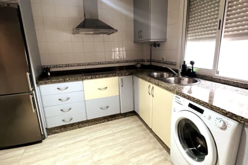 Cocina moderna en apartamento Top Home Integra, Jerez de la Frontera, con muebles blancos, encimera de granito y acero inoxidable