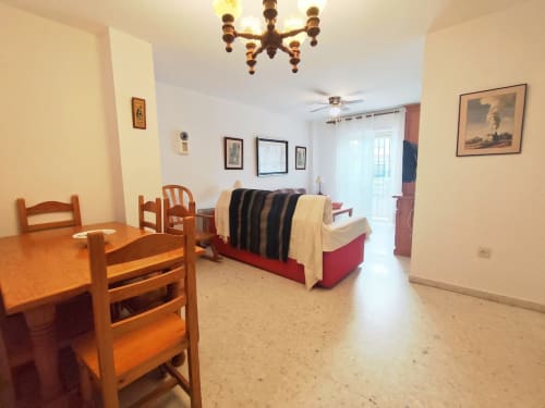 Espacioso apartamento en Top Home Integra de Jerez de la Frontera con mesa de comedor de madera, sofá cama rojo y lámpara de araña