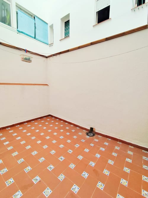 Patio vacío del residencial Top Home Integra en Jerez de la Frontera con suelo de baldosas de barro y balcón azul arriba
