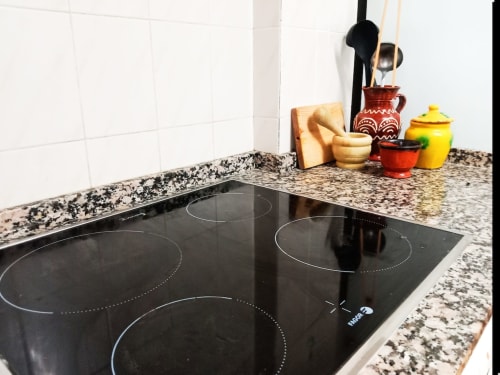 Moderna cocina con encimera de granito y utensilios de cocina en el apartamento Top Home Integra de Jerez de la Frontera