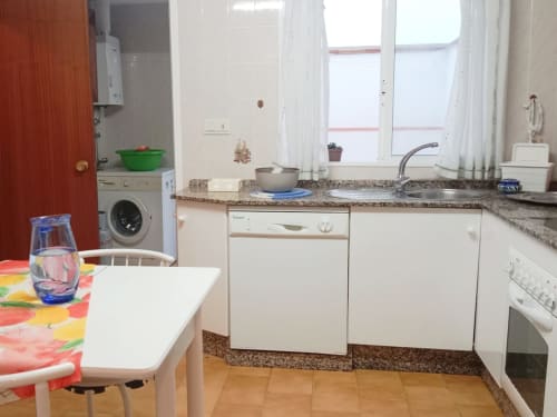 Cocina moderna con zona de comedor en apartamento Top Home Integra en Jerez de la Frontera, con electrodomésticos blancos y granito