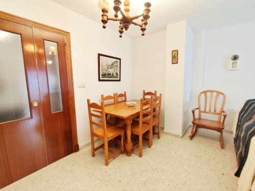 Comedor del apartamento Top Home Integra en Jerez de la Frontera, con mesa de madera, sillas y lámpara de araña tradicional