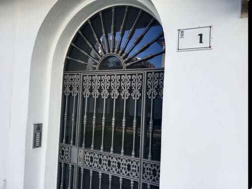 Puerta de metal negro ornamentada con herrería decorativa en la entrada del apartamento Top Home Integra en Jerez de la Frontera