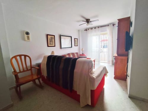 Acogedor salón en Top Home Integra de Jerez de la Frontera con sofá, silla de madera y cuadros decorativos