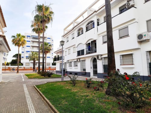 Edificio blanco con palmeras y jardín de flores en Jerez de la Frontera