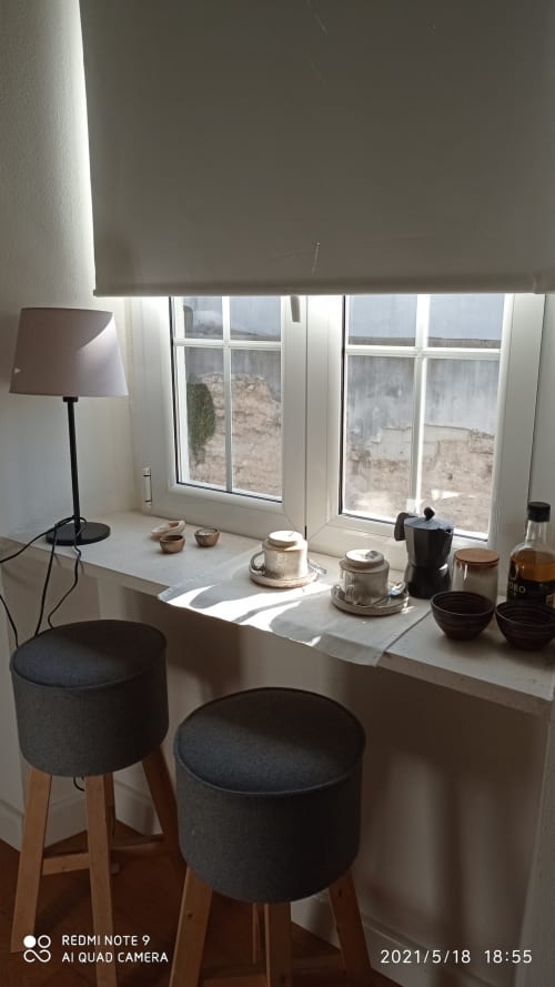 Ventana con asiento en apartamento moderno con vistas al paisaje de Jerez, decorada con lámpara, cerámica y taburetes con cojín