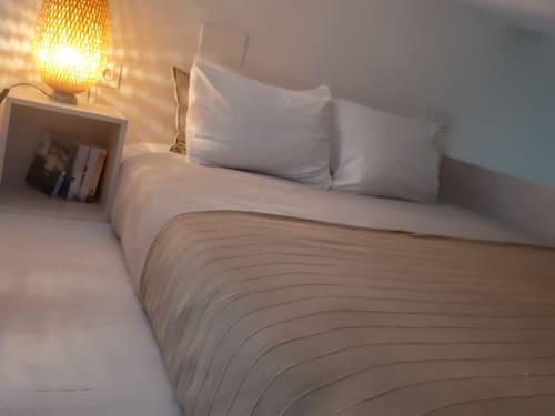 Dormitorio moderno en Top Home Integra, Jerez de la Frontera, con almohadas blancas, ropa de cama neutra e iluminación cálida