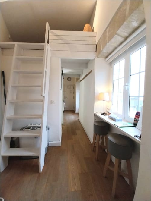 Moderno loft en Jerez de la Frontera con cama elevada, escritorio junto a ventana y suelos de madera