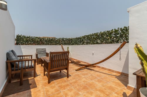 Terraza en la azotea del apartamento Top Home Integra en Jerez de la Frontera con muebles de madera y muros cubiertos de hiedra