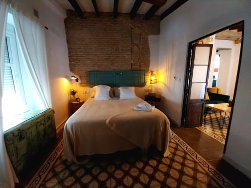 Acogedora habitación en Top Home Integra en Jerez de la Frontera con cabecero verde, iluminación cálida y ladrillo visto