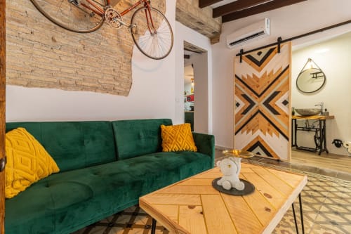 Moderna sala de estar en Jerez de la Frontera con sofá terciopelo verde, mesa de madera y acentos decorativos industriales.