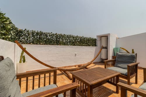 Terraza en la azotea del apartamento Top Home Integra en Jerez de la Frontera con muebles de madera, hamaca y paredes blancas