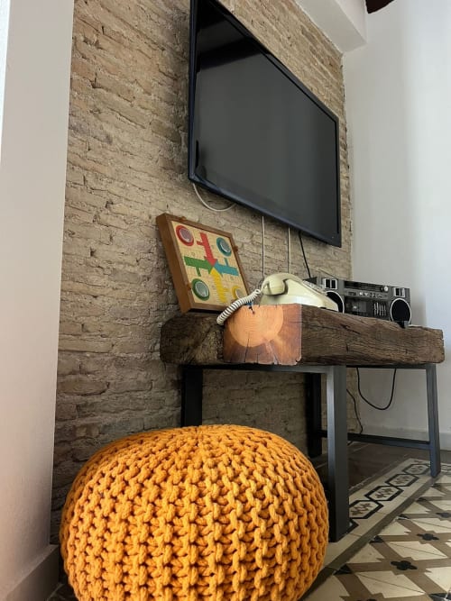 Rincón moderno del apartamento en Top Home Integra Jerez con TV de pared, estantería de madera, radiocasete retro y puf tejido amarillo