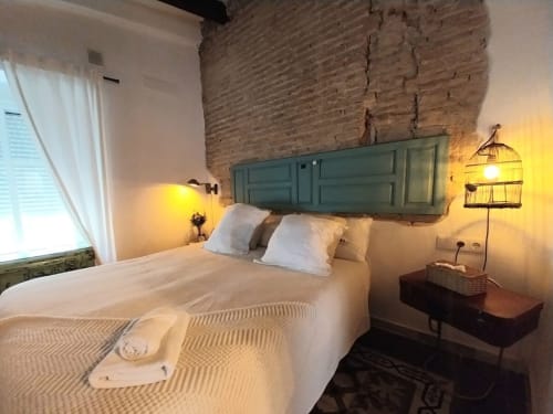 Dormitorio moderno en Top Home Integra de Jerez de la Frontera con cabecero verde, ropa de cama blanca, pared de ladrillo visto y
