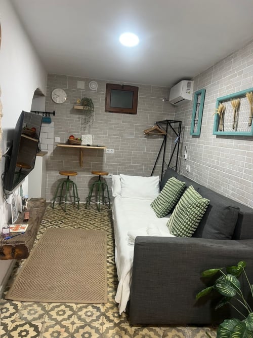Acogedor estudio en Jerez de la Frontera: paredes de ladrillo gris, sofá cama, kitchenette y detalles turquesas