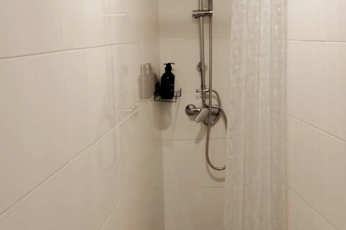 Ducha limpia con azulejos blancos, accesorios cromados y alcachofa en apartamento Top Home Integra, Jerez de la Frontera
