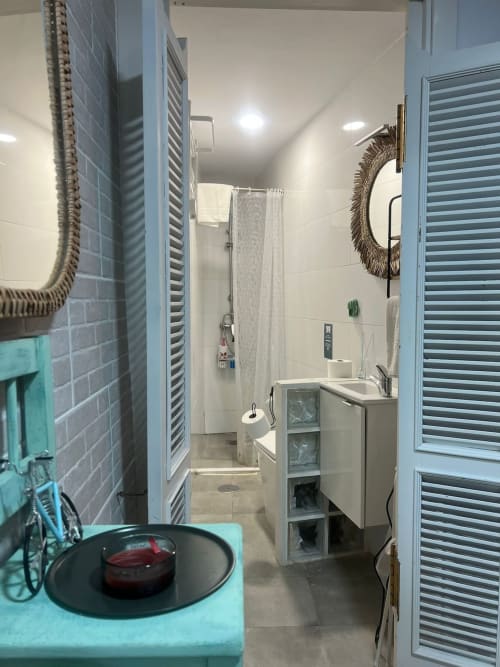 Baño moderno en el apartamento Top Home Integra de Jerez de la Frontera con ducha, lavabo, paredes alicatadas y espejo decorativo