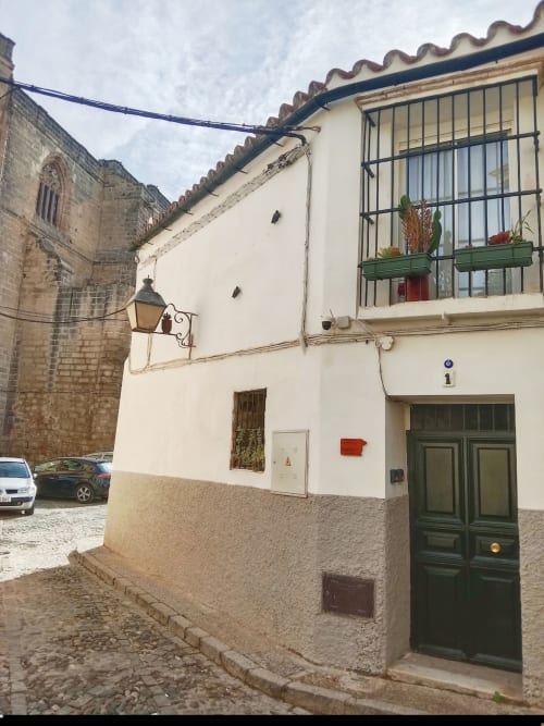 Edificio blanco con puerta verde en Jerez de la Frontera, España. Ventana con rejas y fachada de piedra.