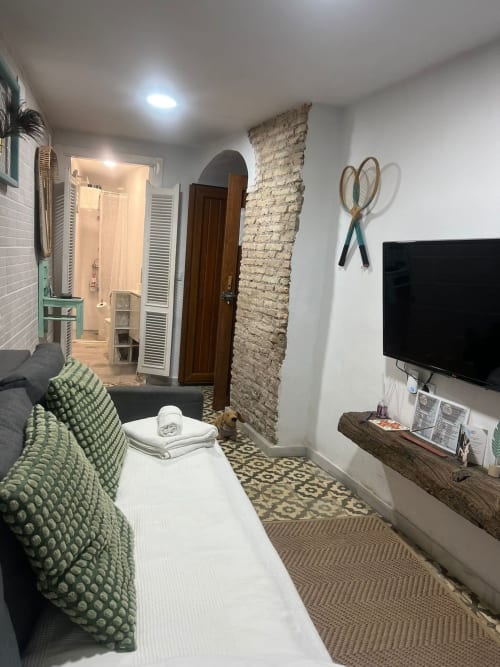 Moderno salón de apartamento en Top Home Integra en Jerez de la Frontera con ladrillo visto, acentos verdes, TV y decoración elegante