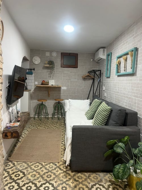 Acogedor estudio en Jerez de la Frontera con paredes de ladrillo gris, sofá, cocina americana y equipamientos modernos