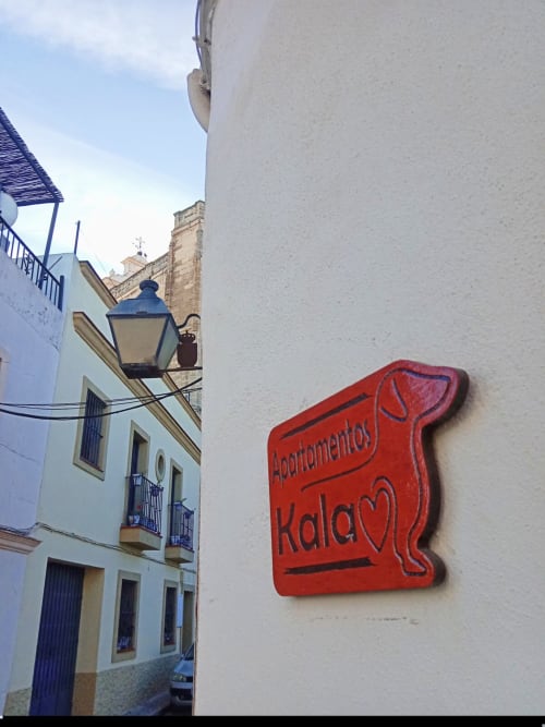Letrero rojo de 'Apartamentos Kalao' en pared blanca de una calle histórica de Jerez de la Frontera