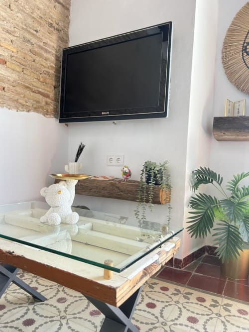 Sala de estar moderna con TV montada en pared, escritorio de vidrio, plantas en macetas y elementos decorativos en Top Home Integra