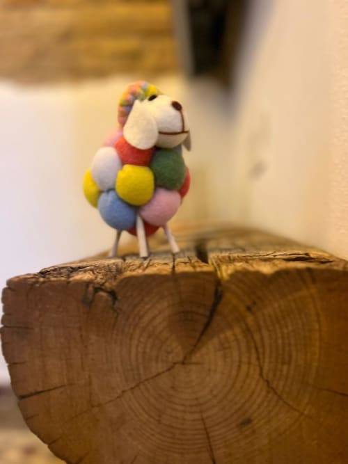 Figura de pájaro artesanal colorida sobre tronco de madera, arte decorativo en el apartamento Top Home Integra de Jerez de la Frontera