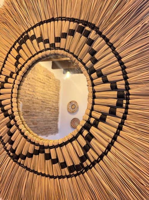 Espejo redondo decorativo con marco de paja tejida y detalles en negro en apartamento de Jerez