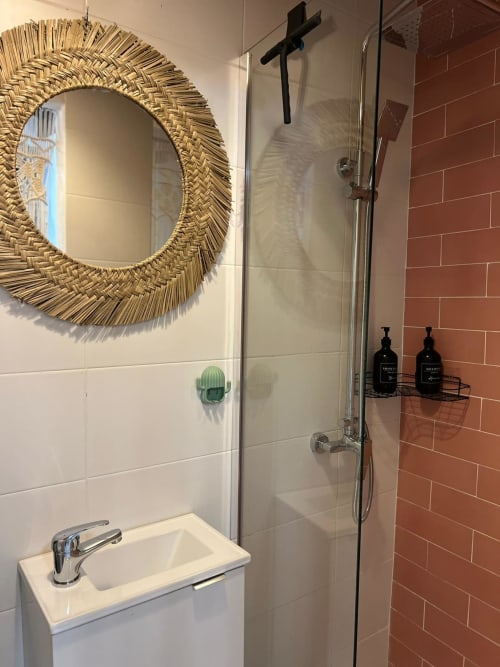 Baño moderno en apartamento Top Home Integra en Jerez con espejo de paja, lavabo blanco, ducha de azulejo terracota y negro